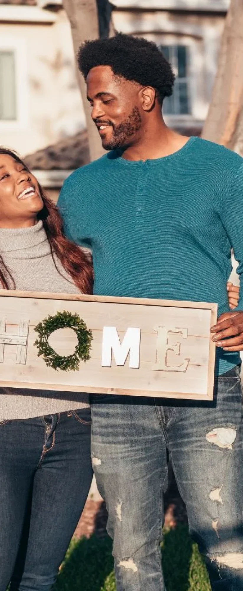 man-in-blue-sweater-holding-a-wooden-home-decoration