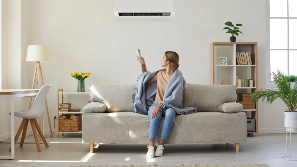 Woman Enjoying Cool Fresh Air In Her Living Room With Air Conditioner On The Wall